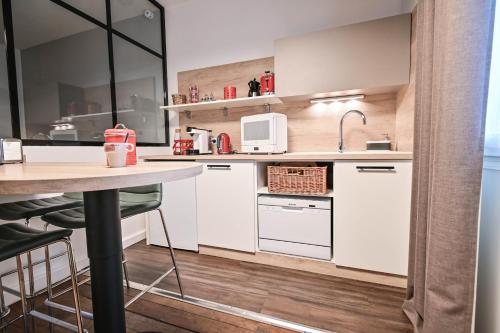 a kitchen with white cabinets and a table at Les cles du 27 Paris in Paris