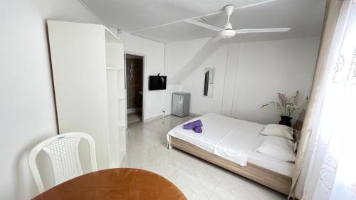 a white bedroom with a bed and a ceiling fan at Sun & Shine Holiday Resort in Flic-en-Flac