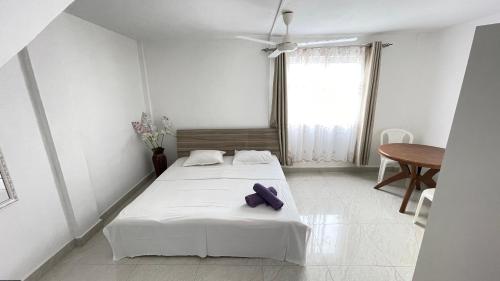 a white room with two beds and a table at Sun & Shine Holiday Resort in Flic-en-Flac