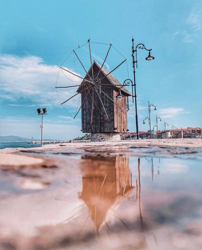 a windmill on the beach with its reflection in the water at Hotel Pacific Palma in Sunny Beach