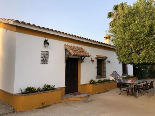 ein kleines weißes Haus mit einem Tisch und Stühlen in der Unterkunft Casa Rural El Laure in Villamartín