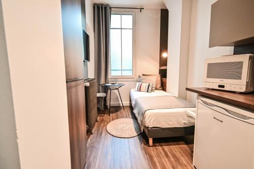 a small room with two beds and a tv at Les cles du 27 Paris in Paris