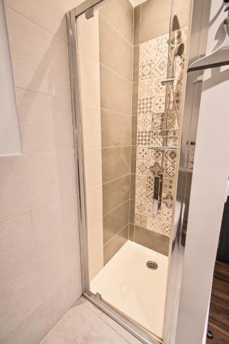 a shower with a glass door in a bathroom at Les cles du 27 Paris in Paris