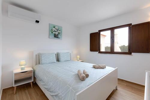 a white bedroom with a bed with two pillows on it at VILLA SOBRAL - Moradia com piscina aquecida para 10 a 12 min de Armação in Porches