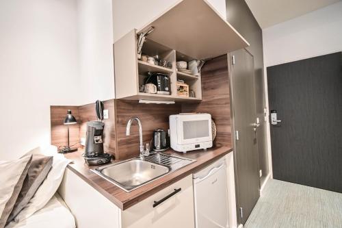 a small kitchen with a sink and a microwave at Les cles du 27 Paris in Paris