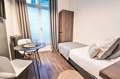 a small room with a bed and a table and a window at Les cles du 27 Paris in Paris