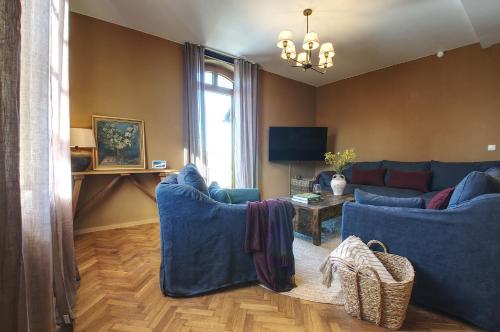 a living room with blue couches and a television at Erzgebirge Suite Altes Rathaus in Cranzahl