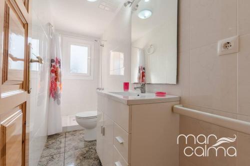 a white bathroom with a toilet and a sink at Villa La Roca by MarCalma in Les tres Cales