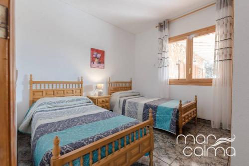 a bedroom with two beds and a window at Villa La Roca by MarCalma in Les tres Cales