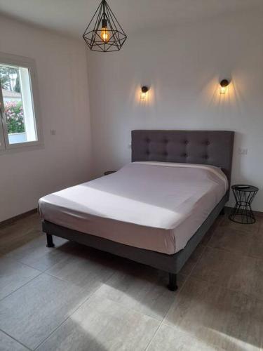 une chambre avec un grand lit avec des draps blancs dans l'établissement Villa avec piscine chauffée entre terre et mer, à Folelli