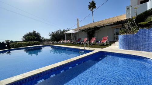 a swimming pool with chairs and a house at Espraguina - Private Pool - 16 Guests - Loulé in Loulé