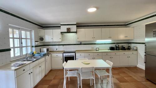 a kitchen with white cabinets and a table and chairs at Espraguina - Private Pool - 16 Guests - Loulé in Loulé