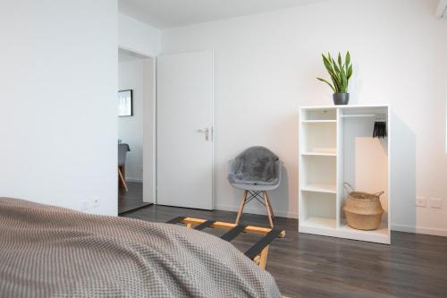 a bedroom with a bed and a chair and a shelf at INN JOY Apartments - Rorschach mit Panoramasicht in Rorschach