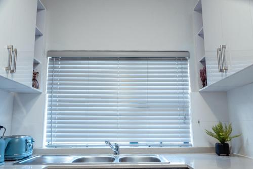 a kitchen with a sink and a large window at Sarona City Apartment A306 in Gaborone
