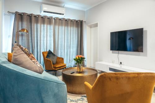 a living room with a couch and chairs and a tv at Sarona City Apartment A306 in Gaborone