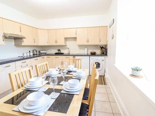 a kitchen with a table with white plates and glasses at Harlech/HUGE Three bedroom/BEST location in Llanbedr