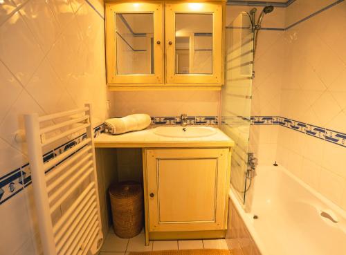 a bathroom with a sink and a cabinet and a tub at Bel appartement, terrasse, piscine, vue sur Golf in Sainte-Maxime