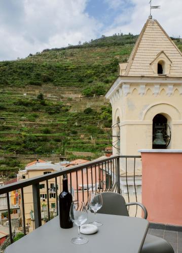 a table with two wine glasses on a balcony at Il Bordone - appartamento con vista mare in Manarola