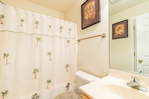 a bathroom with a sink and a shower curtain with palm trees at Sunrise to Sunset in Whalebone