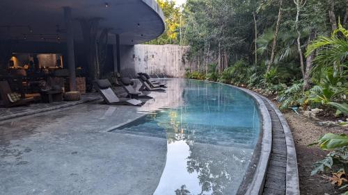 a swimming pool with lounge chairs next to a house at Exclusive Penthouse by Famous Interior Designer By Yeah in Tulum