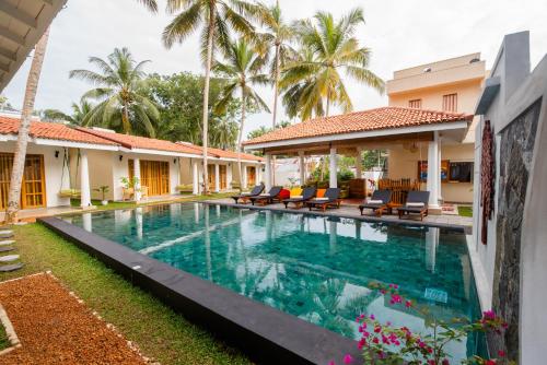 a swimming pool in front of a house with palm trees at Tree of Life Resort in Bentota
