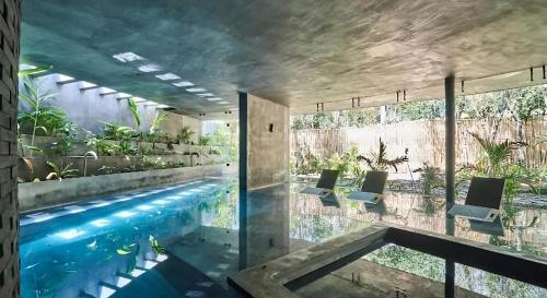 a swimming pool in a house with chairs next to it at Exclusive Penthouse by Famous Interior Designer By Yeah in Tulum