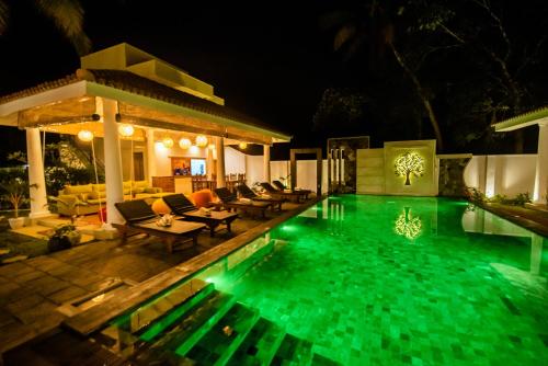 a swimming pool with green lights in a backyard at night at Tree of Life Resort in Bentota