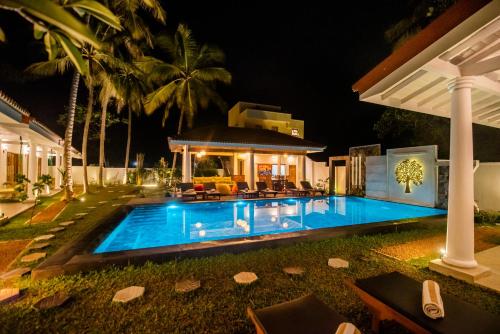 a swimming pool in front of a house at night at Tree of Life Resort in Bentota