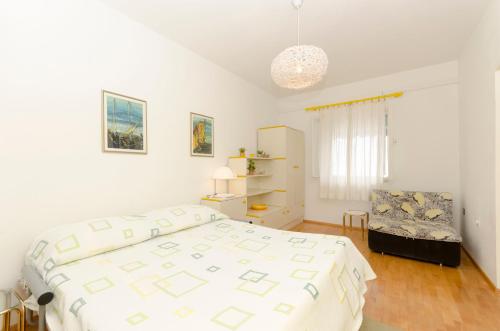 a white bedroom with a bed and a chair at Apartments Simon in Bol