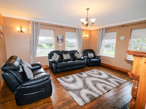 a living room with two leather couches and a rug at Willow Tree Farm House in Newry