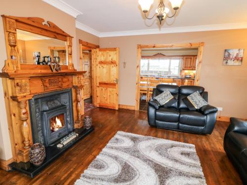 a living room with a fireplace and a leather chair at Willow Tree Farm House in Newry