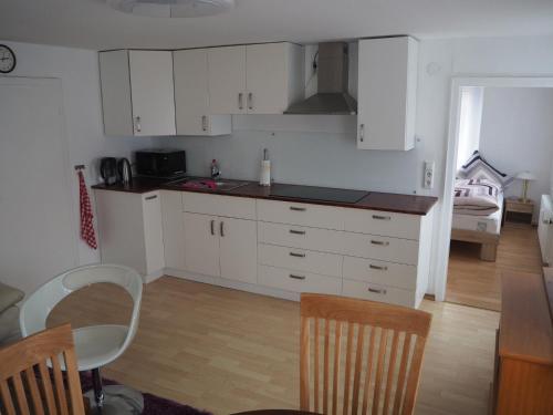 a kitchen with white cabinets and a table and chairs at Ferienwohnung am Bach in Amtzell