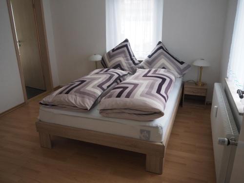 a bed with four pillows on it in a bedroom at Ferienwohnung am Bach in Amtzell