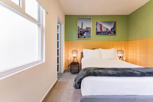 two beds in a room with green walls and a window at Casa Zamora by VH in Mexico City