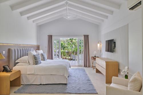 a white bedroom with a bed and a living room at Calabash Hotel in Saint Georgeʼs