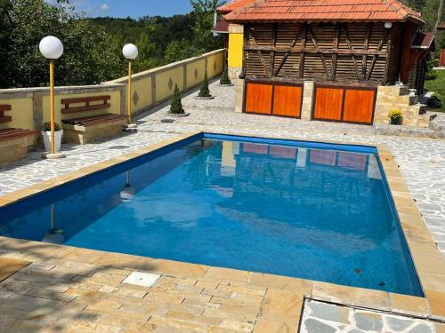 a swimming pool with blue water in a yard at Domacinstvo Ilici ,Gunjaci in Valjevo