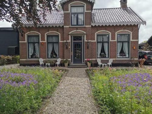 a brick house with white chairs in front of it at B&B Klassiek in Twijzelerheide