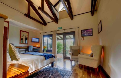 a bedroom with a bed and a desk and a chair at Malachite Manor in Underberg