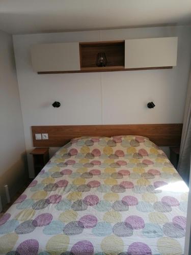 - une chambre avec un lit doté d'un couvre-lit coloré dans l'établissement Mobilhome 6-8 pers Cap Ferret, à Lège-Cap-Ferret