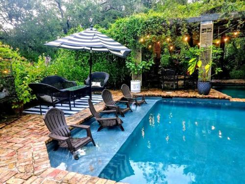 een zwembad met stoelen en een parasol en een tafel met een parasol bij Cedar Oaks Inn The Bath House in Dickinson