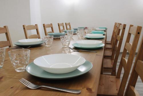una larga mesa de madera con platos y vasos. en Thalassa Casa Vacanza, en Anzio
