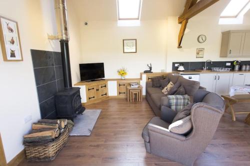 sala de estar con sofá y fogones en Fuesli Lodge - Boutique Cottage at Harrys Cottages en Pen y Clawdd