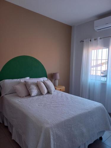 um quarto com uma cama com uma cabeceira verde e uma janela em Hotel y Plaza JMI em Siguatepeque