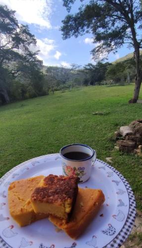 un plato con un trozo de pan y una taza de café en Camping Nhá Chica, en São Thomé das Letras
