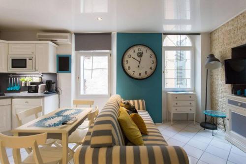 un salon avec un canapé et une horloge au mur dans l'établissement Le Suquet superbe appartement studio, 300m plage, 700 du palais, à Cannes