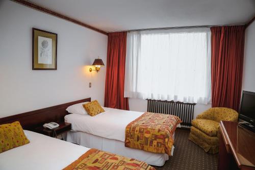 Habitación de hotel con 2 camas y ventana en HOTEL LOS NAVEGANTES en Punta Arenas