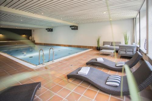 einen großen Pool mit Stühlen und einem Pool in der Unterkunft Boutique-Hotel Weigels Bergfreiheit in Winterberg