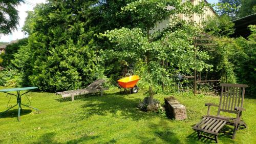 a yard with two benches and a table and an umbrella at GITE AU PETIT RUISSEAU-Etage et combles-maison alsacienne 4 personnes 4 nuitées minimum in Langensoultzbach