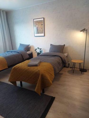 een slaapkamer met 2 bedden en een tafel en een lamp bij Ihastuttava kaksio Pieksämäen keskustasta in Pieksamaki