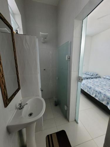 a bathroom with a sink and a mirror and a bed at Aconchego Sagrada face 2 in Aparecida